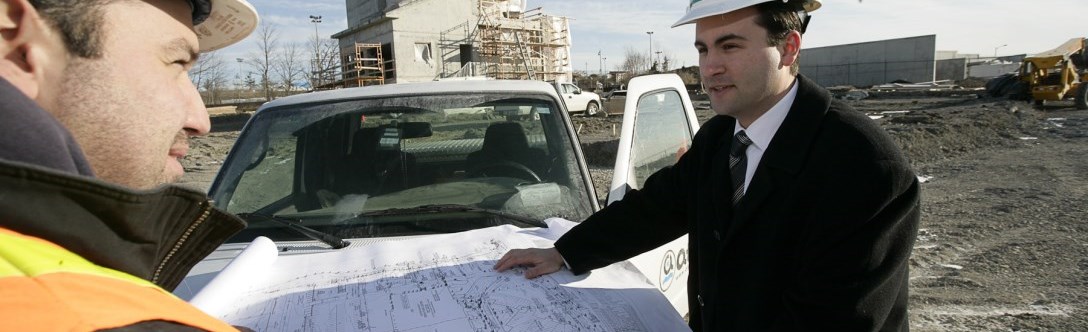 Two men standing looking at blueprints