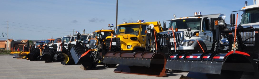 Service trucks like snow plows lined in a row in a parking lot
