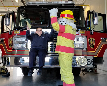 Shanyn Godward with Sparky the Fire Dog mascot in front of a fire truck. 