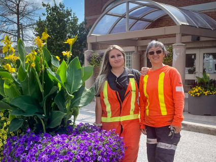 Richmond Hill Horticulture staff standing next to a flower barrel